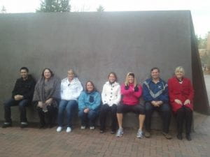 group of 8 HR staff members doing a wall sit against Wright's Triangle sculpture on WWU campus