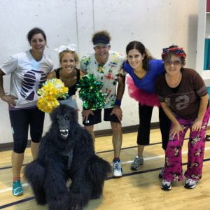 group of 5 people in silly outfits posing with someone in a gorilla costume