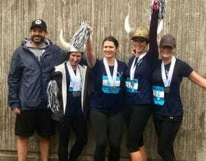 group of 5 runners wearing medals around their necks and viking helmets on their heads holding pompoms at Bellingham Bay Marathon