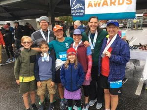 Slower than Molasses Team at the Bellingham Bay Marathon standing in front of the awards table with medals hanging around their necks. 