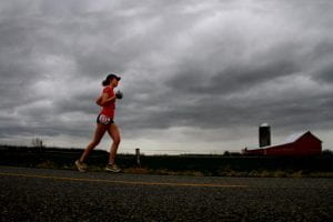 Renee Reynolds running a half marathon outside in Everson running past a red barn
