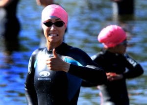 Renee Reynolds is getting ready for the swim in the Clear Lake Triathlon while wearing a wetsuit, black goggles, and a pink swim cap