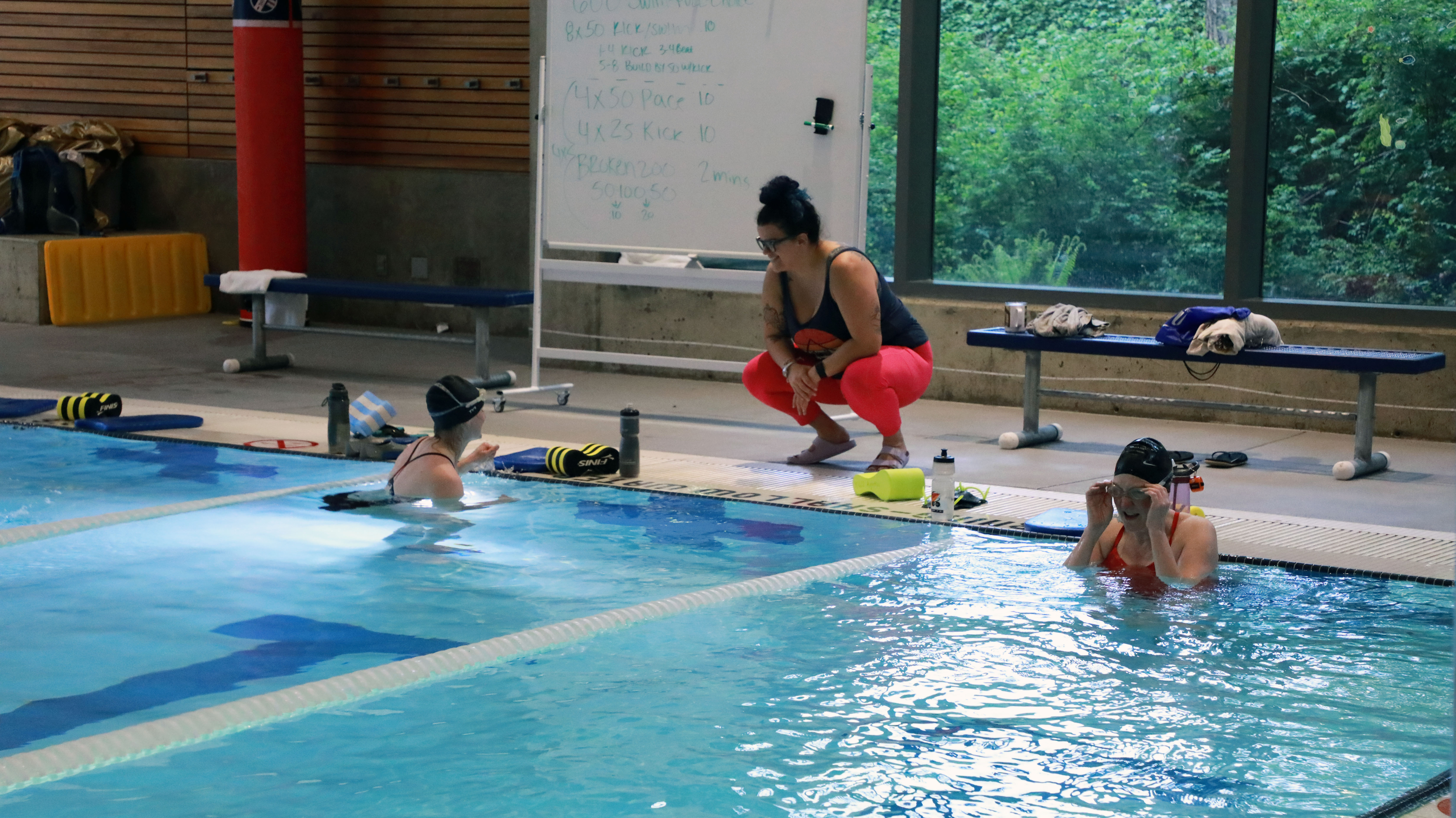 two patrons swimming in the WWU Rec Center pool taking instruction from the swim instructor