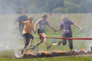 4 people running over hot fiery coals in the Warrior Dash 5K