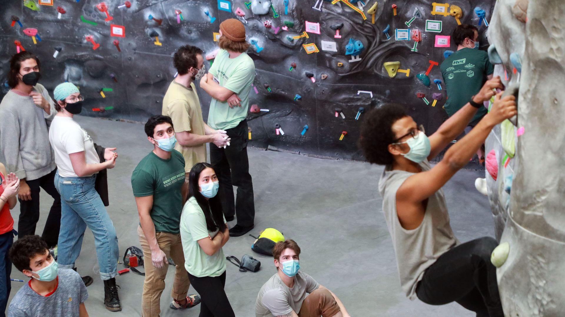 group of students in masks climbing on the rock wall