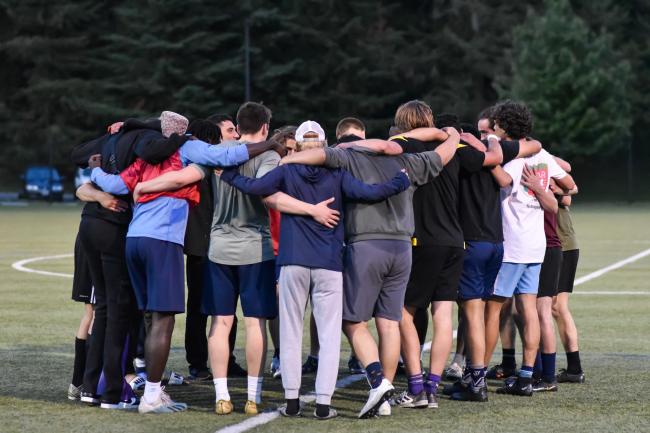 a group of people hugging on the WWU track field after an intramural game