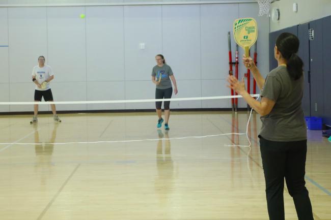 3 people playing a game of pickleball in Carver Gym