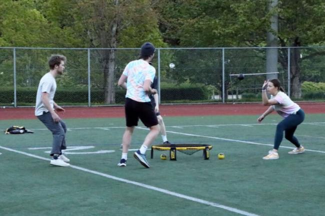 a group of 4 people playing spikeball on the WWU track field