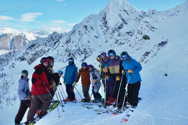 group of 11 skiers on top of a snowy mountains