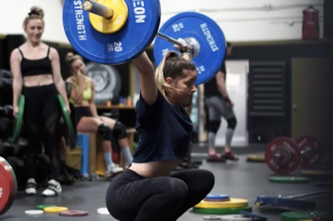 Hailey Thomas wearing an all black outfit lifting a barbell overhead